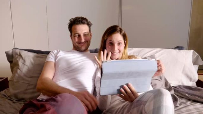 一对恋人，夫妻，视频给朋友或亲戚打电话，并通过平板电脑向他们打招呼。