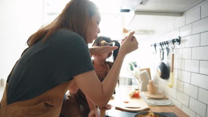 千禧一代的母亲用女儿的帮助手在家做饭煎蛋卷在厨房准备早餐。