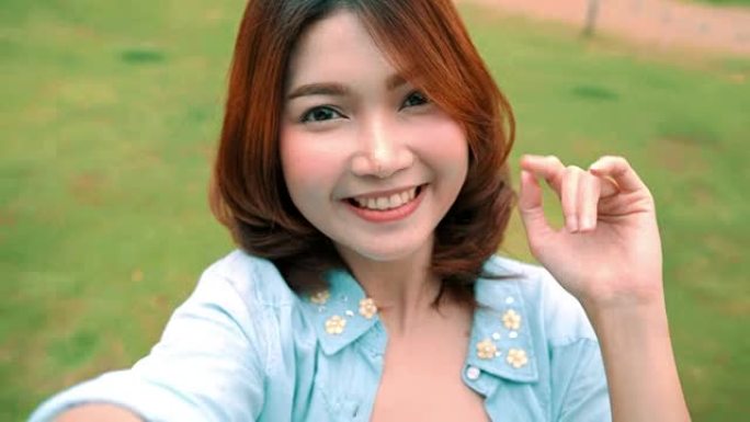 迷人的美丽快乐亚洲女性博客作者使用智能手机进行自拍，并为她的订阅者和她在咖啡馆和餐厅的频道录制食物v