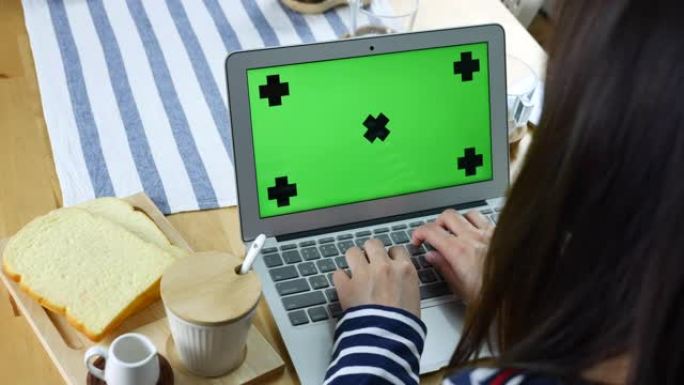 年轻女子在带有绿色模拟屏幕的笔记本电脑上工作