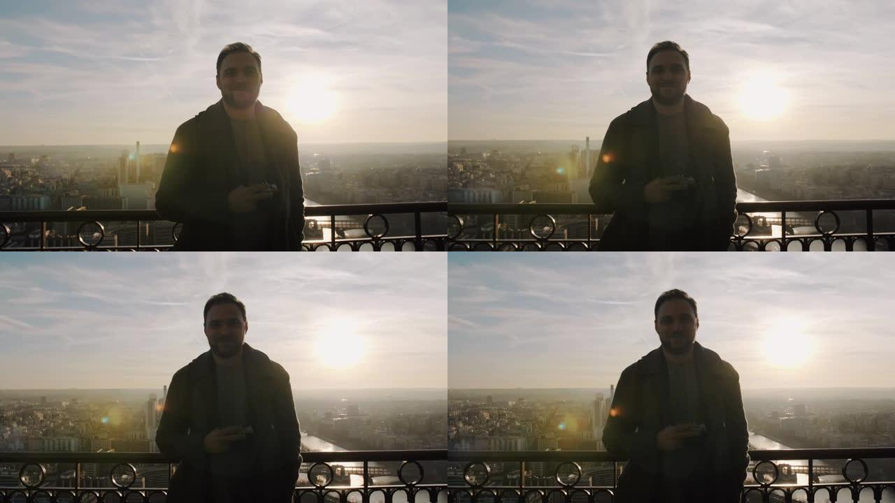 在巴黎埃菲尔铁塔的日落天空全景上，年轻的快乐微笑的高加索游客看着相机。