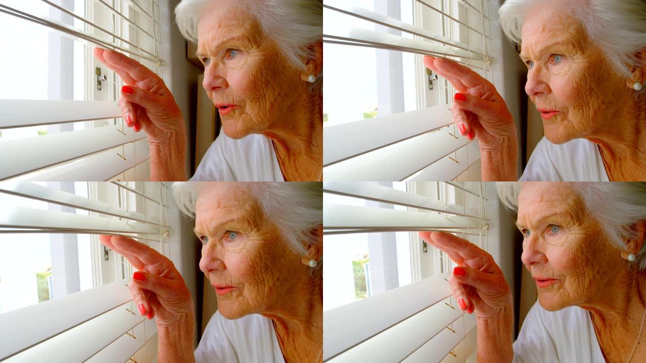 白人高级妇女在家中透过百叶窗观看的特写4k