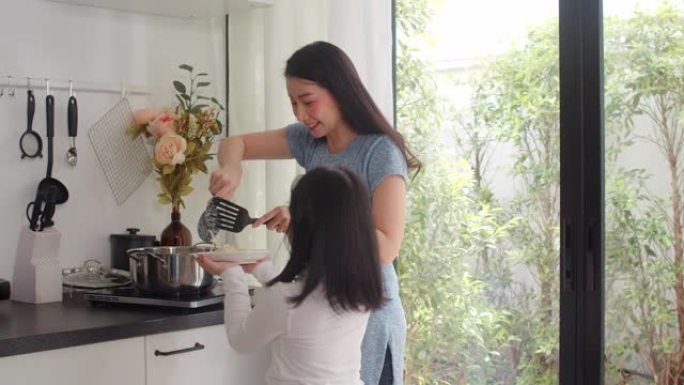 亚洲日本妈妈和女儿在家做饭。生活方式的女性很乐意在家里的厨房里一起做意大利面和意大利面作为早餐。