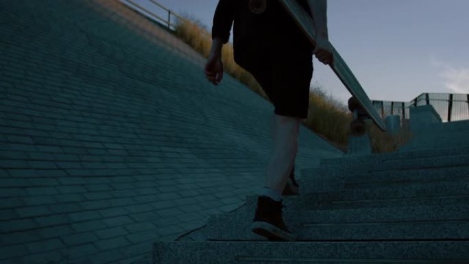 年轻人拿着滑板跑上楼梯的镜头。背景时尚现代潮人区