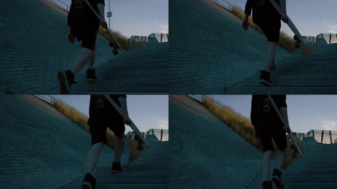 年轻人拿着滑板跑上楼梯的镜头。背景时尚现代潮人区