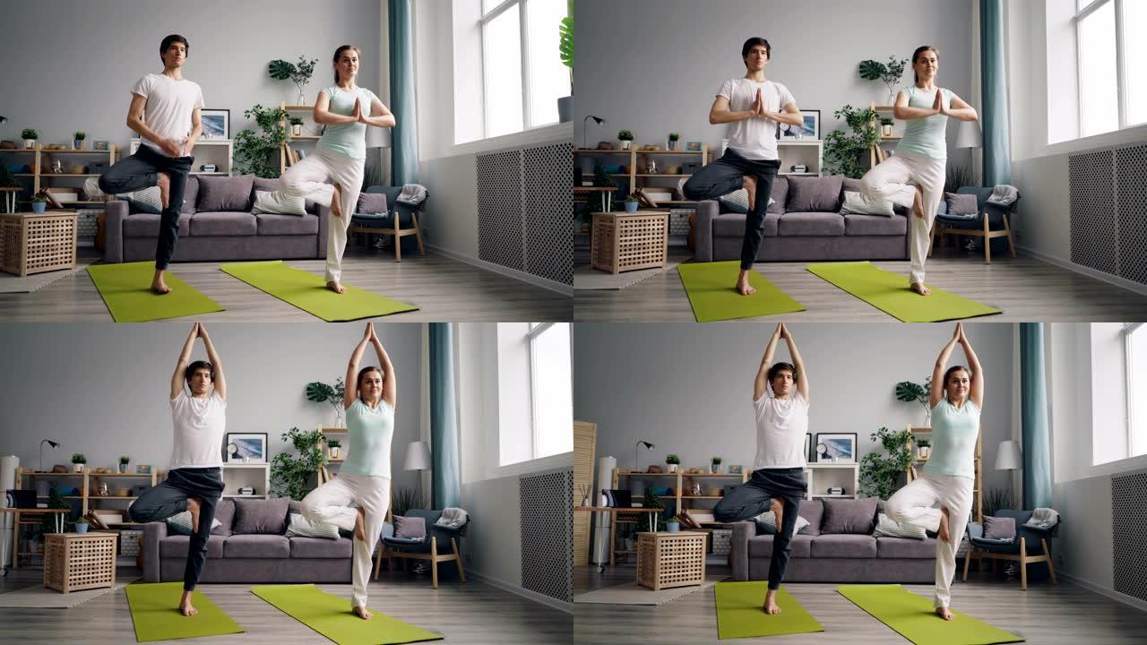 年轻的家庭在公寓里练习瑜伽，单腿在垫子上保持平衡