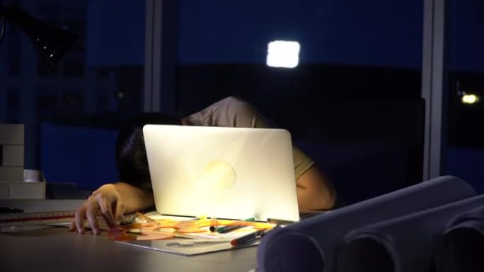 迷人的亚洲女性工作到很晚，在电脑显示器桌面前的桌子上认真思考