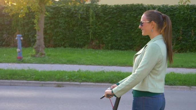 肖像: 开朗的女人骑着电动踏板车看着相机。