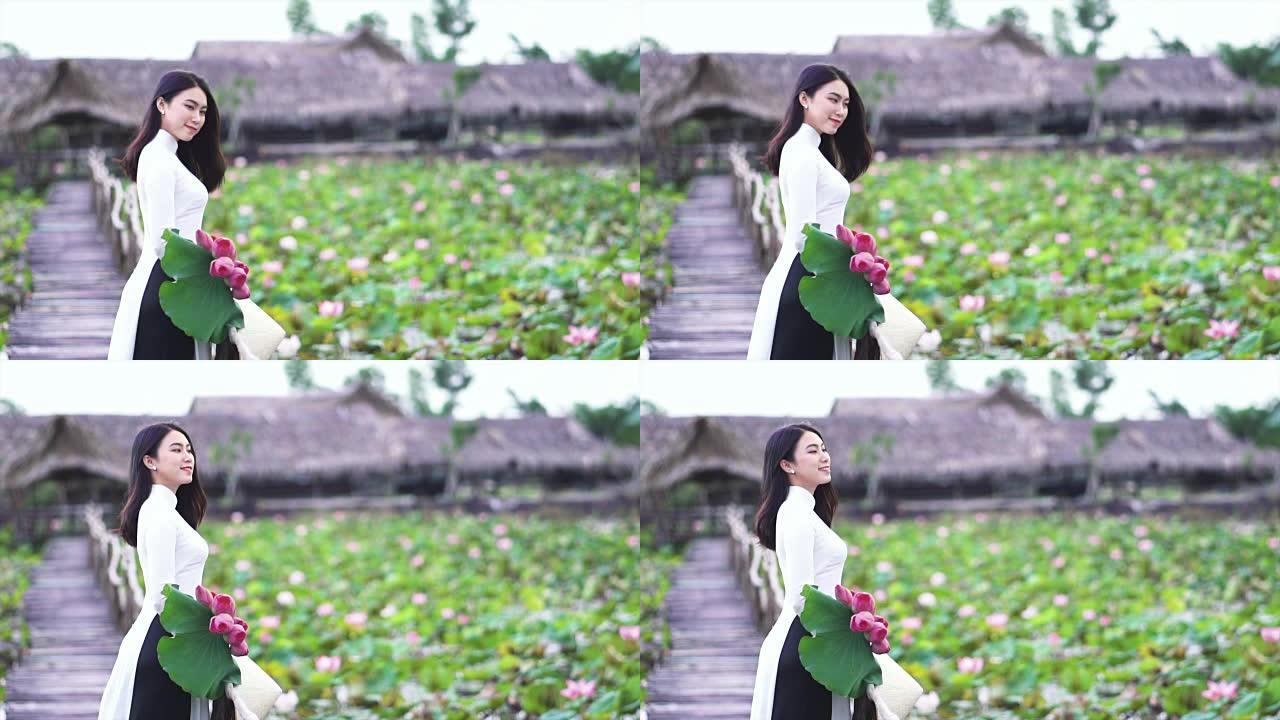 4k慢动作镜头越南美女肖像手持粉红色莲花在大莲花湖木桥上微笑，越南，亚洲或东南亚旅行概念