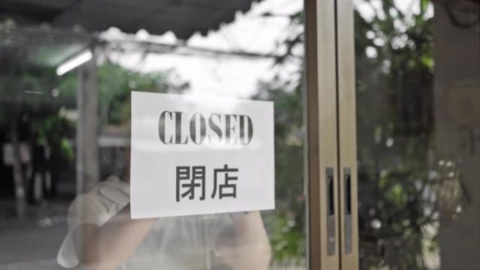 女孩正在关闭商店标志，由于新型冠状病毒肺炎病毒大流行爆发，商店关闭