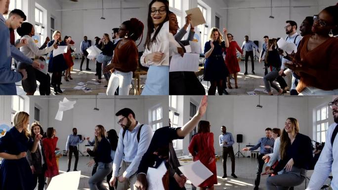 现代多民族办公室的快乐成就庆祝派对。多元化的商人在时尚的工作场所跳舞。
