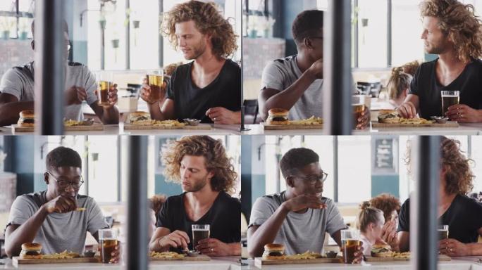 两个男性朋友坐在酒吧吃饭，用慢动作的啤酒吐司