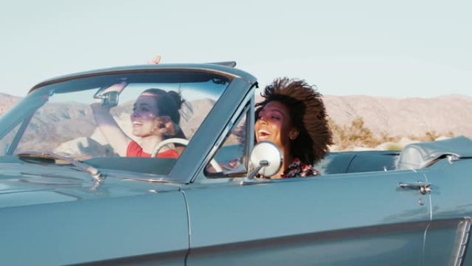 兴奋的女性朋友在高速公路上驾驶敞篷车