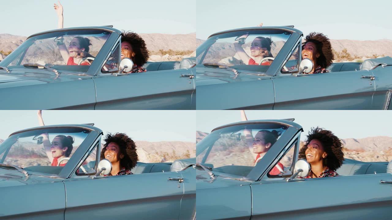 兴奋的女性朋友在高速公路上驾驶敞篷车