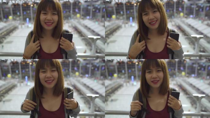 快乐的亚洲女人在国际机场候机楼微笑着对着镜头，女游客准备度假。生活方式女性快乐假期在机场概念。
