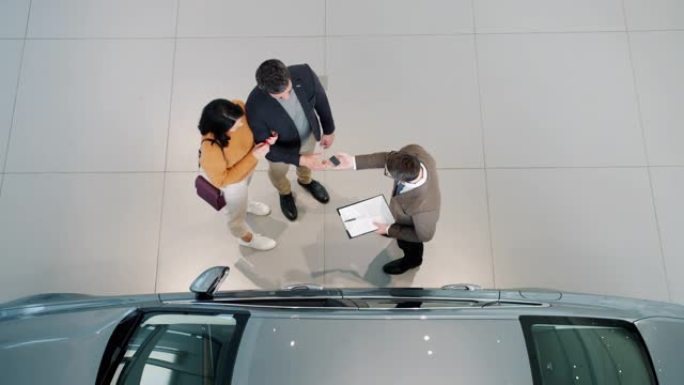 购车者与经销商在经销商室内拥抱握手的俯视图