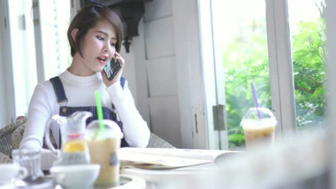 4k分辨率漂亮的亚洲女人坐在咖啡店里打电话