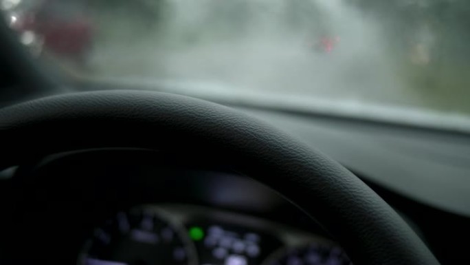 大雨期间的汽车与紧急帮派在一起。雨下从挡风玻璃到红绿灯的景色。UHD 4K