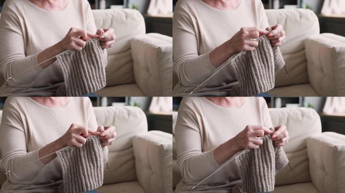 沙发上拿着针编织围巾的老妇人，特写镜头