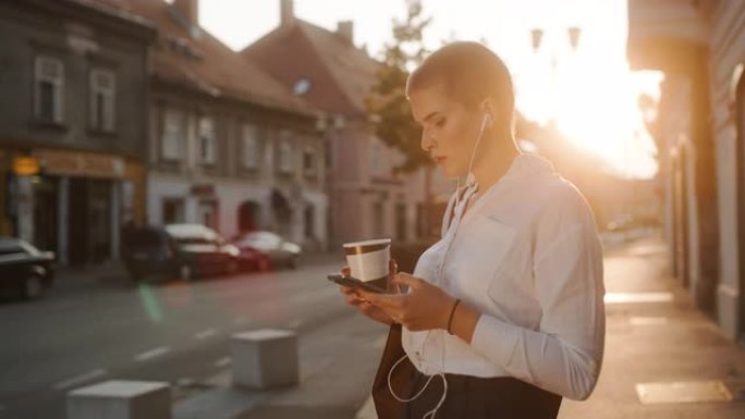现代女商人在城市的人行道上使用智能手机