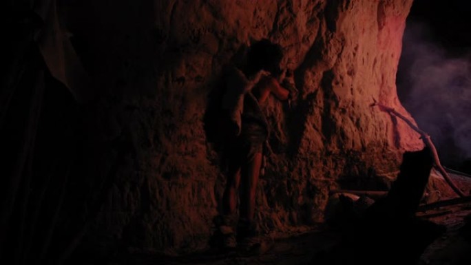 原始的史前尼安德特人穿着动物皮在夜间绘制动物并在墙壁上抽象。用岩画创造第一个洞穴艺术，用火照亮的岩画