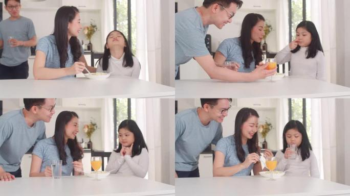亚洲日本家庭在家里吃早餐。亚洲快乐的爸爸，妈妈和女儿早上在厨房的桌子上吃意大利面喝橙汁。