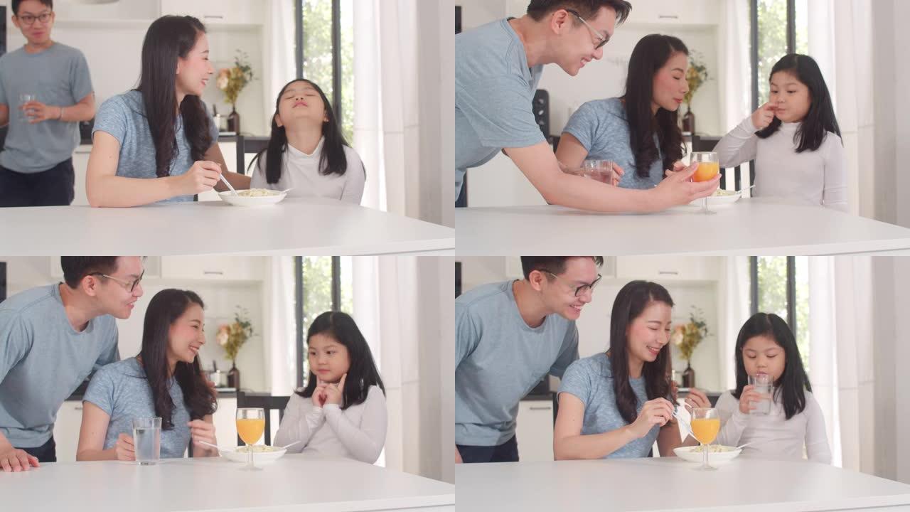 亚洲日本家庭在家里吃早餐。亚洲快乐的爸爸，妈妈和女儿早上在厨房的桌子上吃意大利面喝橙汁。