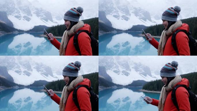在加拿大冰碛湖使用手机的年轻女性旅行者