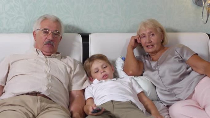 老年夫妇和孙子躺在床上看电视