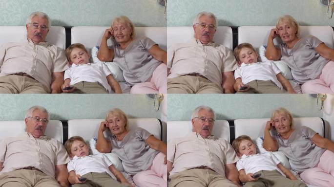 老年夫妇和孙子躺在床上看电视
