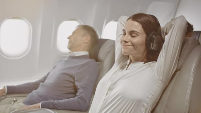 戴着耳机的女商人在飞机上放松
