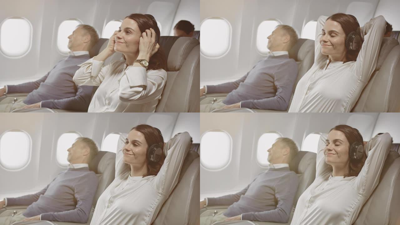 戴着耳机的女商人在飞机上放松