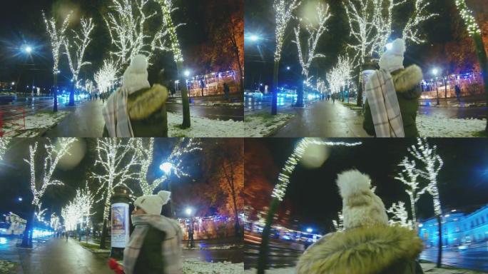 女士女士在奥地利维也纳的夜晚沿着照明的冬季城市人行道行走