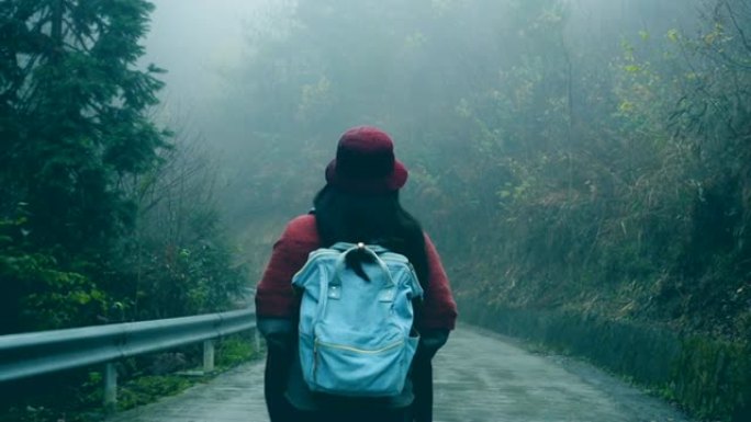 背着背包走在森林路上的旅行者