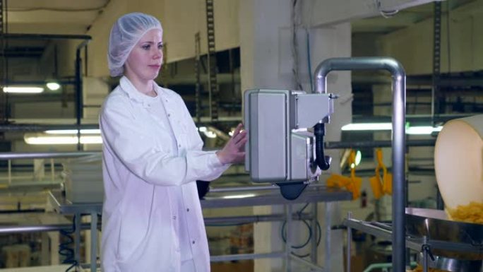 年轻女子在食品生产设施中使用工厂设备工作。