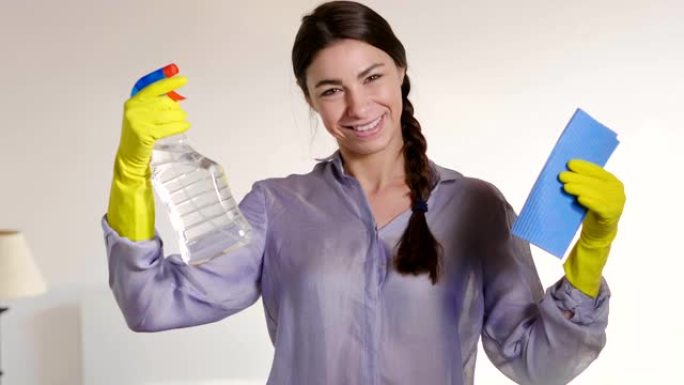 一个努力打扫房子的美丽女人故意用喷雾剂和布清洗玻璃。