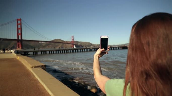 女人用智能手机拍照金门大桥