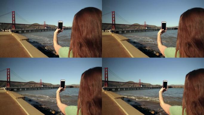 女人用智能手机拍照金门大桥