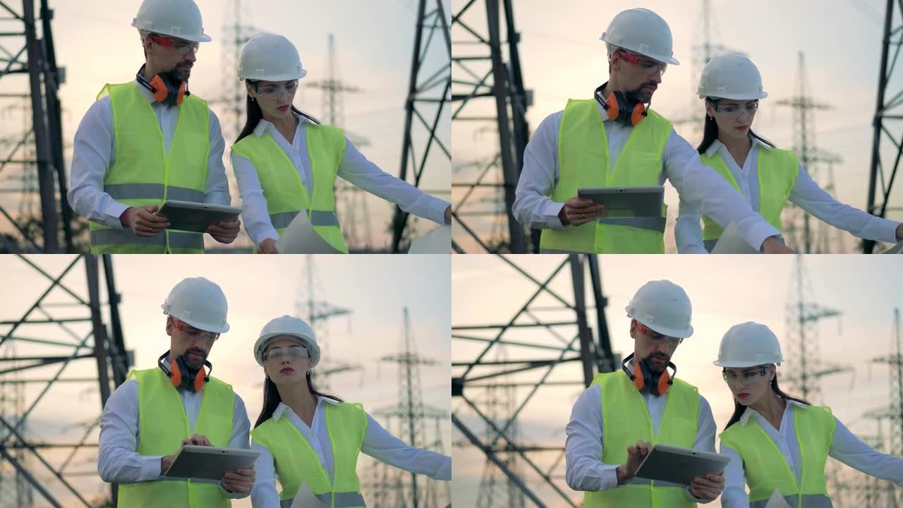 安全帽男女工程师在能源变电站检查中讨论建设项目。
