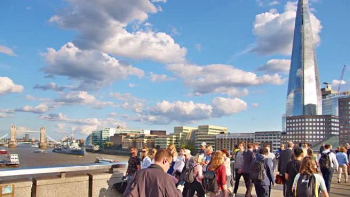 休闲的人们穿过塔桥穿过伦敦桥。戏剧性的天空。