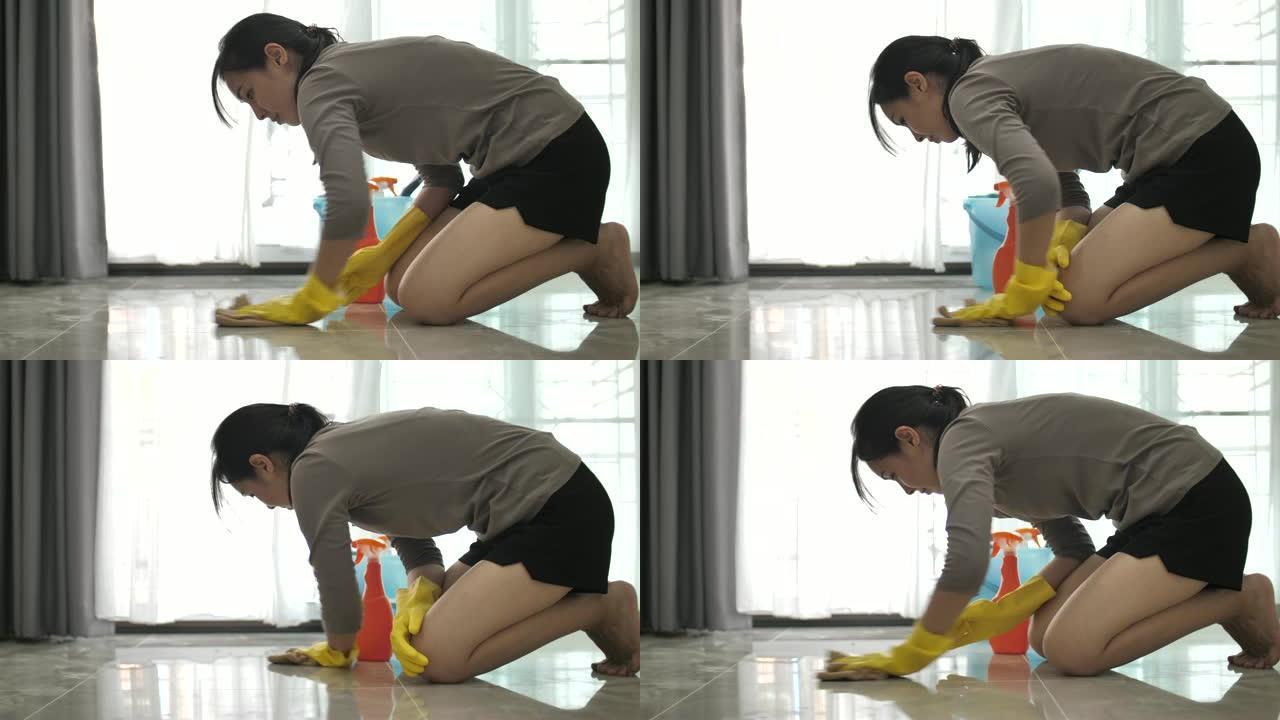 亚洲妇女试图用喷雾清洁产品去除地板上的污渍