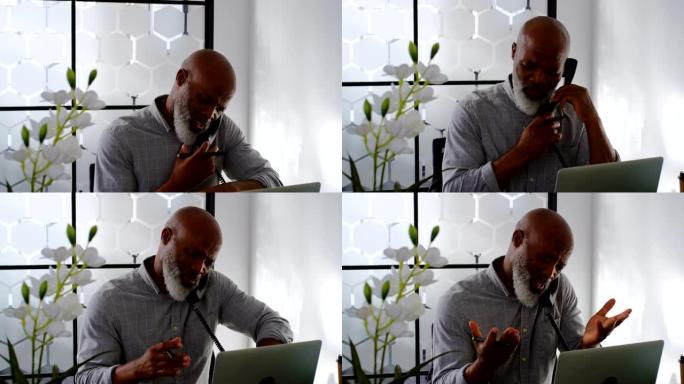男子在4k桌上使用笔记本电脑时在固定电话上交谈