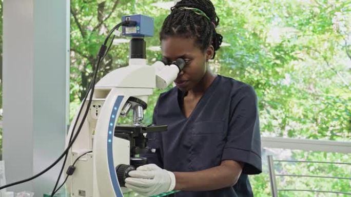 非裔美国女性病理学家在医学实验室使用显微镜的肖像