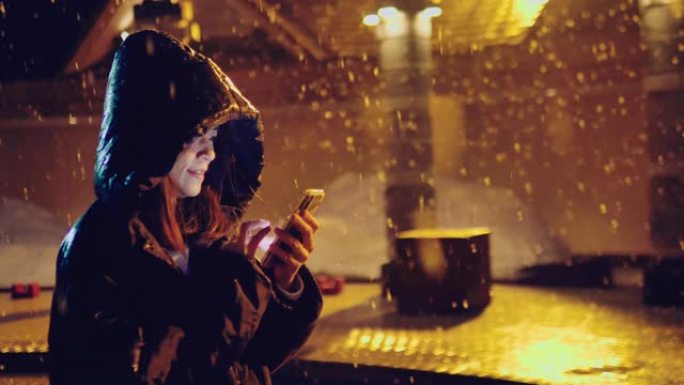 带手机的年轻亚洲女孩在带圣诞灯的冬季街道上