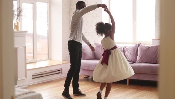 非洲父亲牵着女儿的手在室内跳舞