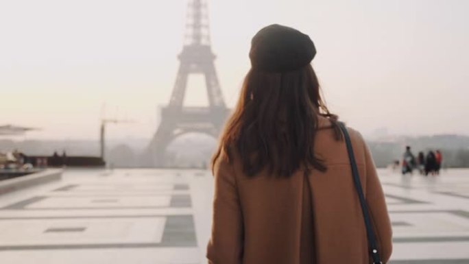 镜头跟随美丽的旅行者女人在度假慢动作中走向巴黎特罗卡德罗的迷雾埃菲尔铁塔。