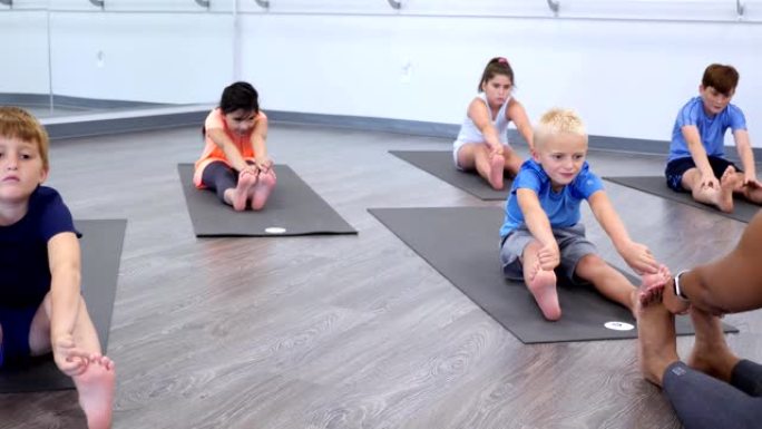 瑜伽老师教孩子在瑜伽课上伸展运动