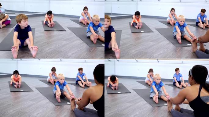瑜伽老师教孩子在瑜伽课上伸展运动