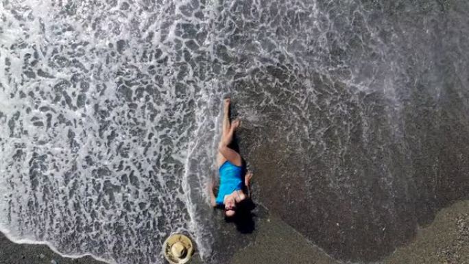 一个女人喜欢度假，躺在海滩上的水中。暑假概念。
