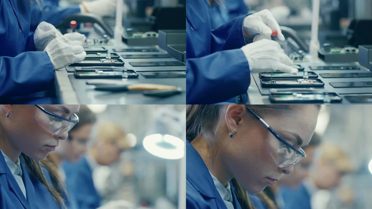 一名穿着蓝色工作服和防护眼镜的电子工厂女工人的特写镜头，用螺丝刀组装智能手机。高科技工厂设施，后台有